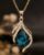 Gold plated teardrop zirconia pendant necklace featuring a blue crystal flame design